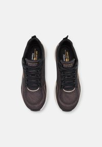 Black mesh sneakers with a textured upper, black laces, and cream-colored soles. Features subtle accents in a rose gold hue.