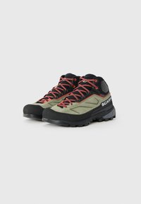 Et par grønne og sorte vandresko med røde snørebånd, robuste såler og "Scarpa"-branding på siden.
