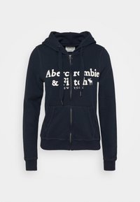 Felpa con zip di colore navy realizzata in tessuto misto cotone. Presenta una tasca a marsupio, un cappuccio con coulisse e un logo bianco sul petto.