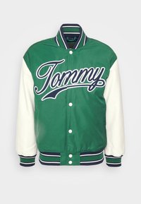 Zielono-biała kurtka varsity z wyraźnym logo "Tommy", zapięciem na zatrzaski oraz ściągaczami z granatowo-zielonymi paskami.