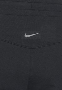 Zwarte sportleggings van Nike met een gladde textuur, voorzien van een zilveren logo op de tailleband en subtiele stikdetails bij de naden.