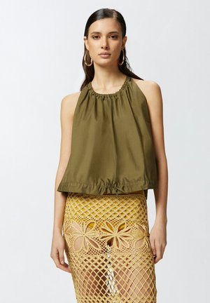 Top senza maniche verde oliva con scollatura arricciata e orlo con cordoncino, abbinato a una gonna gialla all'uncinetto con ritagli floreali.
