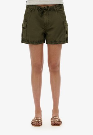Khaki cargoshorts met een trekkoord in de taille, twee zijzakken en een licht gerimpelde zoom. Gecombineerd met bruine slipper sandalen met ronde accenten.