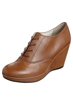 Brun kilesko i læder med snøredesign foran og glat afrundet tå, vinklet for at vise ydersiden og sålkanten.