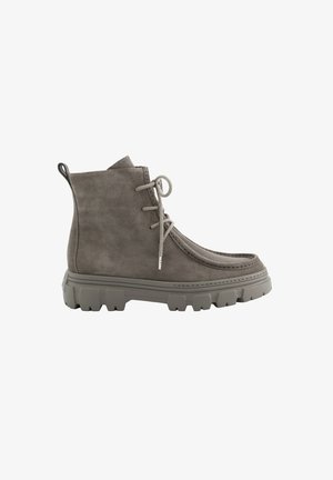 Stivaletto grigio in camoscio con suola spessa carrarmato, punta tonda, tre occhielli per i lacci e linguetta sul tallone, mostrato di profilo laterale.