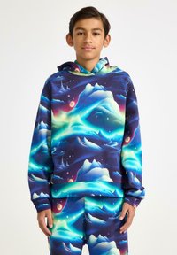 Felpa con cappuccio caratterizzata da una vivace stampa galattica con onde blu, viola e verdi, realizzata in tessuto morbido; abbinata a pantaloni con fantasia.