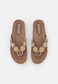 Sandali in tessuto marrone con suola piatta, dotati di un embellissement circolare di perline in tonalità oro, bianco e marrone lungo la fascetta.