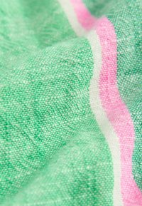 Tissu avec une texture tissée verte, présentant un motif à rayures roses et blanches. Tissu doux, léger et légèrement transparent.