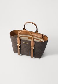 Bruine monogram tote bag met tan leren handvatten en accenten. Beschikt over een open bovenkant, een binnenzak met rits en goudkleurige hardware details.