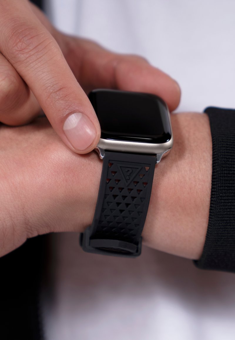 Smartklocka med ett svart gummiband som har ett texturerat triangulärt mönster, silverfärgat rostfritt stålfodral och en slät svart skärm.