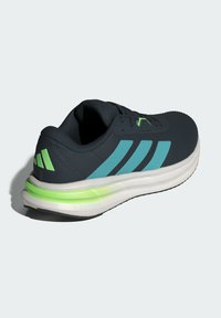 Chaussure de course pour homme avec une partie supérieure en maille lisse bleu marine, des rayures teal, une semelle blanche et un accent vert lime sur la semelle intermédiaire. Dispose d'une technologie d'amorti.