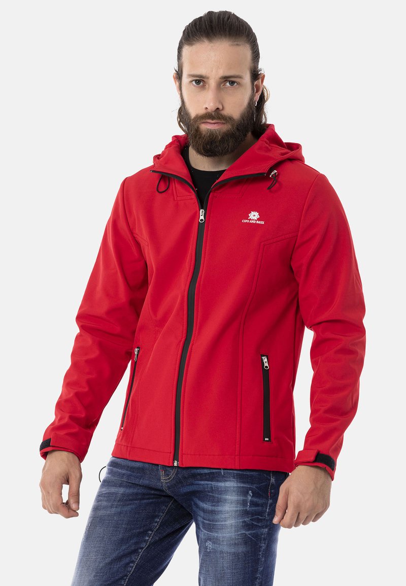 Rote Softshell-Jacke mit Kapuze, durchgehendem Reißverschluss, zwei Seitentaschen, schwarzen Reißverschlussakzenten und verstellbaren Kordel-Details. Schlichtes Design.