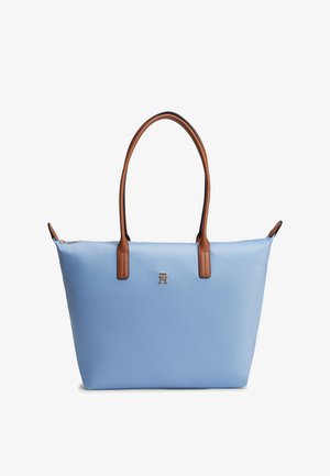Svetlo modra torba za na rame s rjavimi ročaji in majhnim kovinskim logotipom na sredini sprednje strani, z zadrgo za zapiranje ter gladko teksturo.