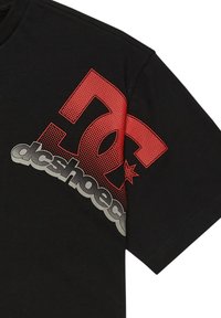 Černé bavlněné tričko s velkým červeným a šedým grafickým logem "DC" s tečkovaným vzorem a textem "dcshoes". Krátké rukávy, kulatý výstřih.