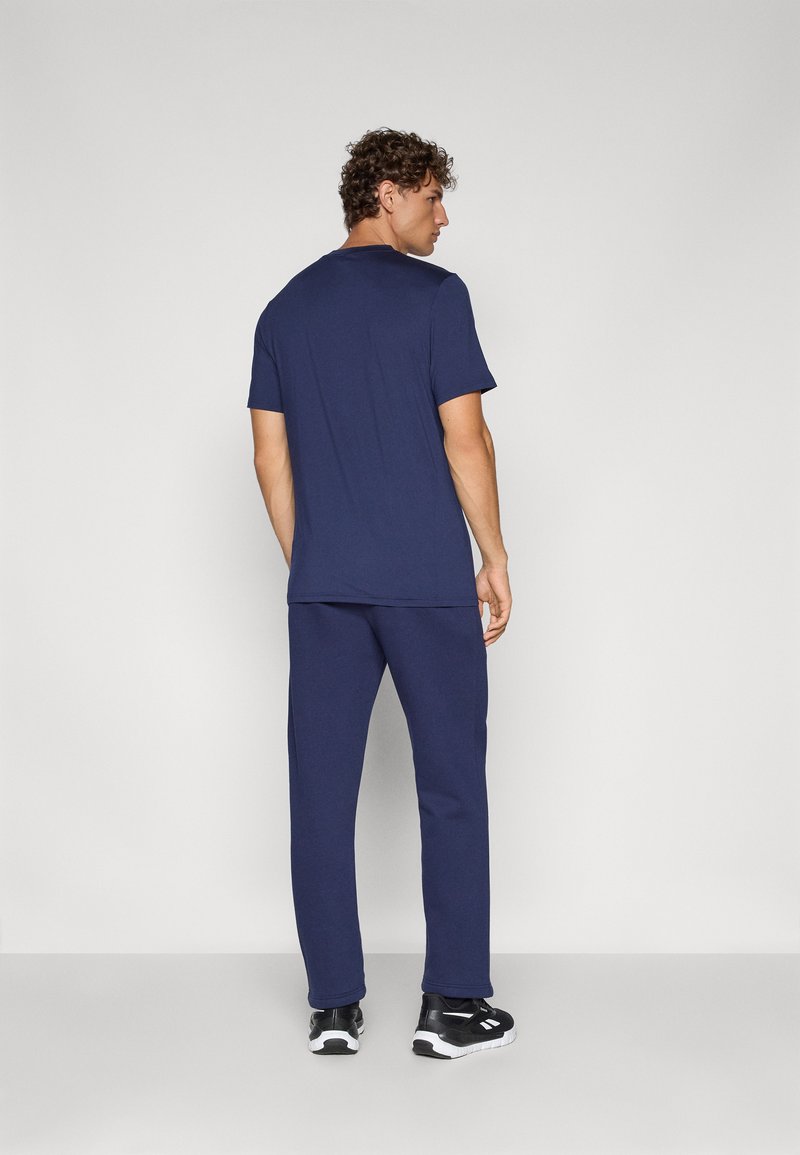 Camiseta de algodón azul marino de mangas cortas y pantalones deportivos a juego en azul marino, con un ajuste relajado. Zapatillas negras con detalles blancos.