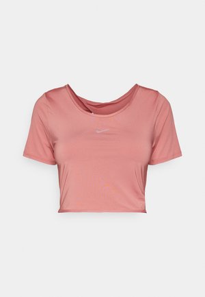 Růžové zkrácené tričko s krátkým rukávem, vyrobené z hladkého materiálu. Obsahuje kulatý výstřih a malou bílou nášivku Nike na přední straně.