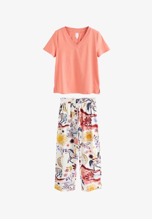 Top coral cu mâneci scurte şi decolteu în V, asortat cu pantaloni albi cu croială largă şi imprimeuri colorate cu soare, cal şi flori.