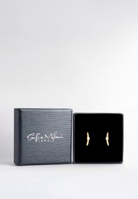 Scatola di gioielli nera con orecchini a bottone dorati all'interno, ciascun orecchino con un piccolo gioiello circolare, brandizzati Sofia Milani Jewels sulla parte superiore.