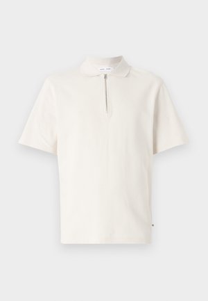 Krāsā off-white īsām piedurknēm polo krekls ar rāvējslēdzēja apkakli. Izgatavots no mīksta auduma ar tīru, minimālu dizainu un bez redzamām rakstām.