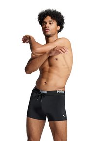 Schwarze Sportshorts mit verstellbarem Bund, ausgestattet mit einem Puma-Logo auf der linken Seite und einem weichen, strukturierten Material für Flexibilität.