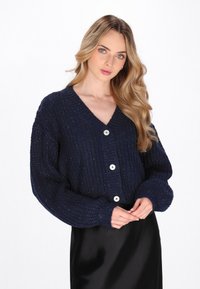 Cardigan lavorato a maglia color navy con scollatura a V, caratterizzato da un motivo testurizzato, maniche lunghe e quattro grandi bottoni bianchi sul davanti.