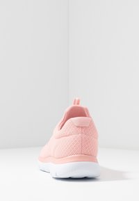 Lichtroze sportschoen van ademend mesh materiaal, met een afgeronde vorm, gevoerde hiel en witte zool. Voorzien van een trekband voor gemakkelijk aan- en uittrekken.