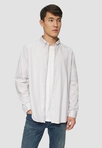 Button-up overhemd met pastel gestreept patroon, lange mouwen en een kraag; gecombineerd met een wit T-shirt en denim jeans; relaxte pasvorm.
