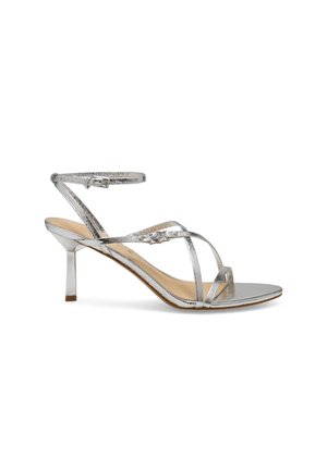 Sølv højhælet sandal med tynde krydsende stropper, ankelrem med spænde og åbent tå-design på hvid baggrund.