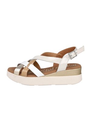 Sandalias de cuña con tiras blancas, doradas y metálicas. Plantilla suave en color bronceado, correa de tobillo ajustable y suela de plataforma texturada.