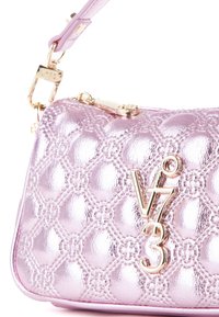 Bolso de mano metálico rosa con diseño acolchado, que presenta un logo y cierre en tono dorado. Textura suave y forma estructurada con una correa desmontable.