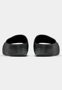 Μαύρα παπούτσια slip-on με ραφιναρισμένη εξωτερική επιφάνεια, σχέδιο ανοιχτού πάνω μέρους με στρογγυλή μορφή, επίπεδες σόλες και υφή στο κάτω μέρος για καλύτερη πρόσφυση.