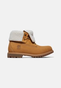 Bottes imperméables beige avec un doux col en fausse fourrure blanche. Présentent des lacets et une semelle en caoutchouc avec un motif de grip texturé.