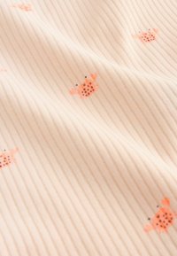 Tissu côtelé beige doux avec de petits motifs de crabes orange éparpillés sur la surface, créant un design subtil et ludique.