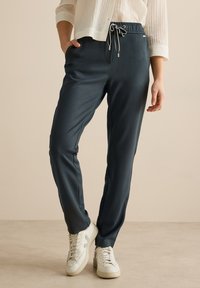 Mörkblå, lätta joggingsbyxor med elastisk midja och snörning. Har sidfickor och en tapered design på benen.