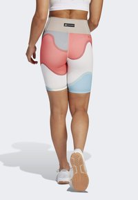 Krótke legginsy z wysokim stanem, z kolorowym falistym wzorem w kolorach czerwonym, jasnoszarym i niebieskim. Wykonane z elastycznego, gładkiego materiału.