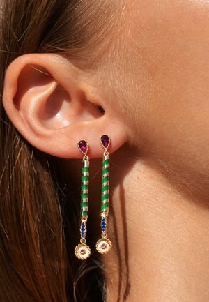 Goldene Ohrringe mit abgehängten Anhängern und grünen sowie weißen gestreiften Details. Sie sind mit lila und blauen Edelsteinen verziert und enthalten blumenförmige Elemente.