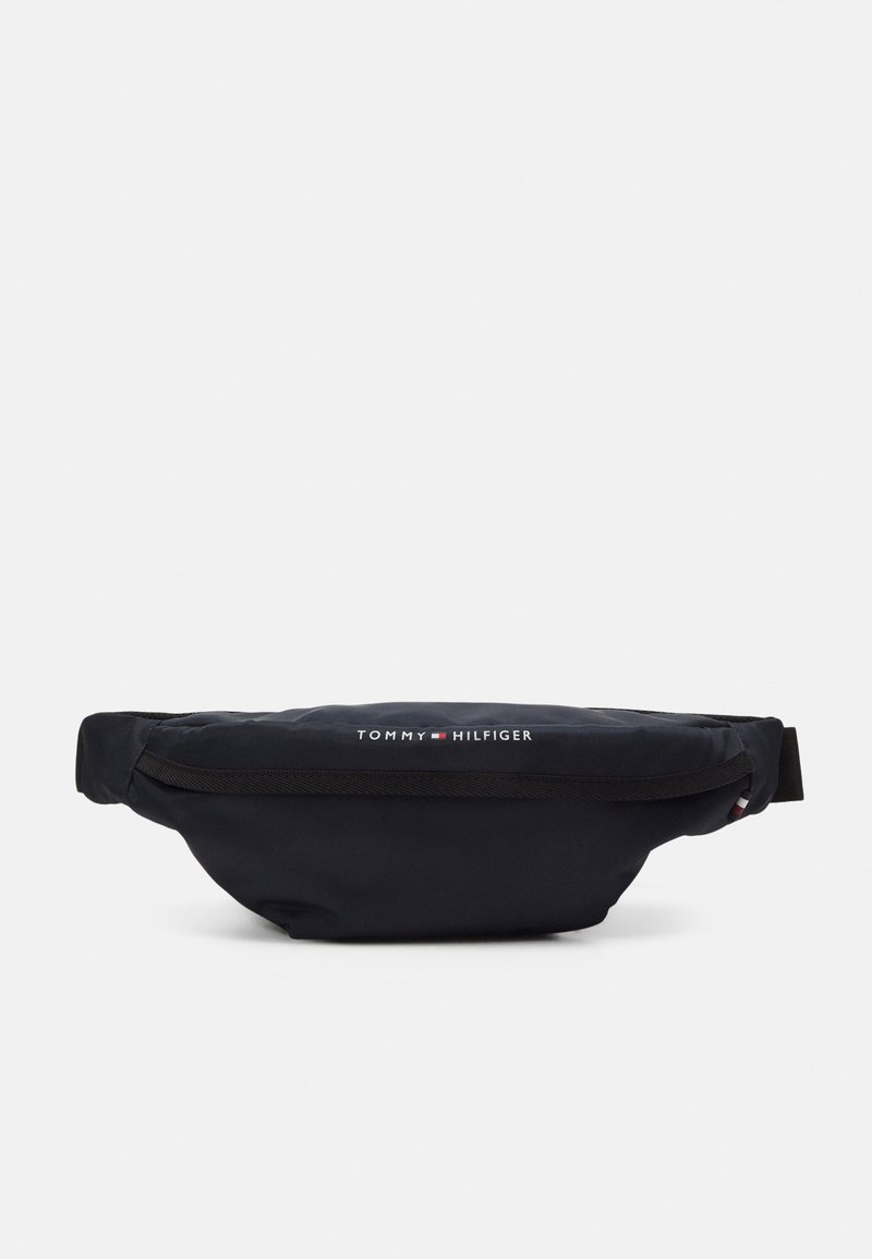 Marsupio in nylon nero a forma curvata, dotato di una tasca frontale con zip e logo bianco "TOMMY HILFIGER". Tessuto testurizzato per una maggiore durata.
