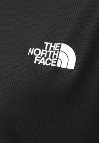 Μαύρο υφαντό ύφασμα με λευκό λογότυπο "THE NORTH FACE" και σχεδίαση σε σχήμα τριών τετάρτων κύκλου εκτυπωμένα πάνω του.