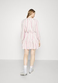 Stripet kjole med rosa og hvite vertikale striper, elastisk midje, vide skjørt, lange ermer og samlet detalj ved skuldrene.