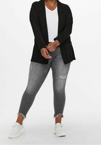 Musta pitkähihaisen avoimen bleiserin päällä valkoinen t-paita, yhdistetty kuluneisiin harmaisiin skinny-farkkuihin ja valkoisiin lenkkareihin. Rentoa, teksturoitua kangasta.