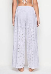 Pantaloni bianchi larghi con dettagli in broderie anglaise, caratterizzati da ritagli e motivi floreali. Vita elastica per il comfort.