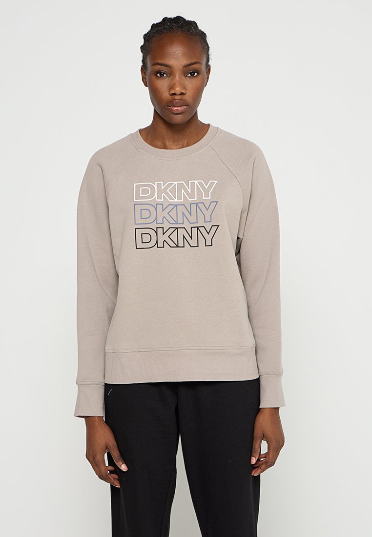 Beżowa bluza z okrągłym dekoltem, posiada raglanowe rękawy i wielokolorowe logo "DKNY" w różnych odcieniach na przodzie. Wykonana z miękkiej tkaniny bawełnianej.