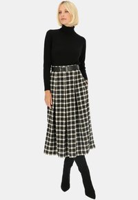 Czarny golf w połączeniu z midi spódnicą w czarno-białą kratę, z kieszeniami i szerokim czarnym paskiem, uzupełnioną przez czarne kozaki do kolan.