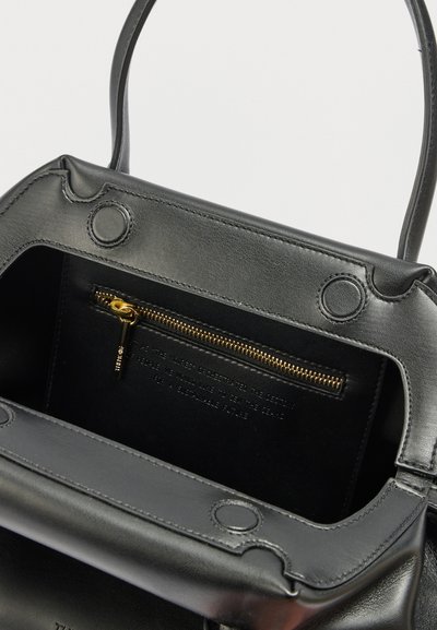 Μαύρη δερμάτινη τσάντα χειρός ανοιχτή για να δείξει το εσωτερικό με χρυσή τσέπη με φερμουάρ και μαγνητικά κουμπώματα στο καπάκι.