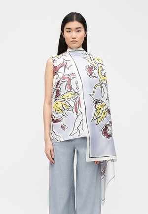 Frau trägt ärmelloses Oberteil und passenden Schal mit buntem Cherub- und Flügelmotiv, kombiniert mit hellblauen Hosen mit weitem Bein.