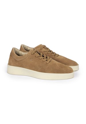 Paar braune Wildleder-Sneaker niedrig mit Schnürverschluss und dicken weißen Gummisohlen auf weißem Hintergrund.
