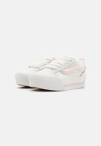 Baskets blanches avec des accents roses, présentant un upper texturé, un bout rond et une semelle épaisse blanche. Design à lacets avec un détail de logo sur le côté.