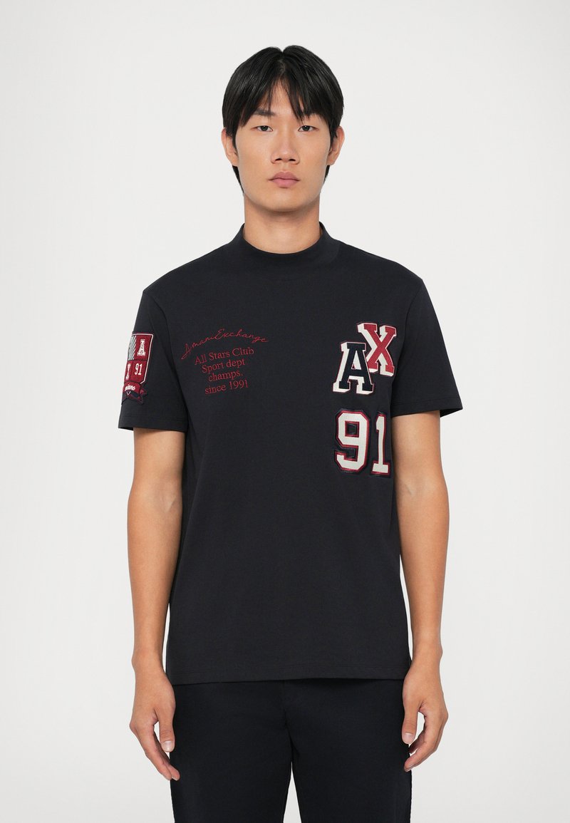 T-shirt nera a maniche corte con accenti rossi ricamati, presenta i design "AX" e "91" sul davanti e un colletto alto.