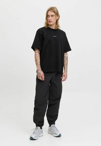 Sort bomuld t-shirt med en afslappet pasform, korte ærmer og et lille logo. Parret med sorte bukser med elastiske manchetter og sideaccentuer.