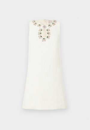 Vestido branco com um tecido texturizado, apresentando um decote bordado com contas florais e um detalhe em forma de olho-chave na frente.